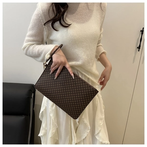 Detailed view of coffee floral clutch with geometric print and wrist strap on model