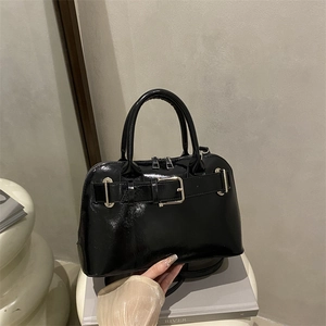 Minimalist black glossy faux leather tote bag with silver metal buckles and top handles