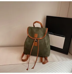 Detailed macro view of the green suede backpack with dark brown leather trim and metal buckle