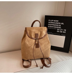Detail of vintage brown suede backpack featuring leather straps and metal buckle accents