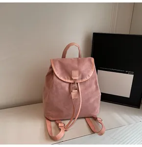 Close-up of pink suede backpack featuring a classic top handle and durable flap closure