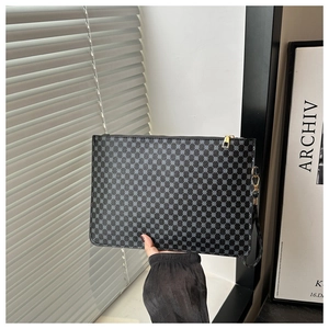 Detail of grey geometric pattern handbag with gold metal zipper and wrist strap close-up