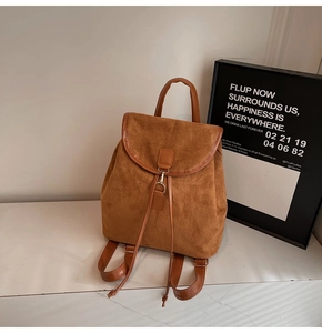 Detail of a retro brown suede backpack with leather trim and gold metal buckle closure