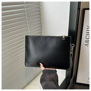 Detail showing smooth black PU leather clutch bag texture and premium gold zipper handle