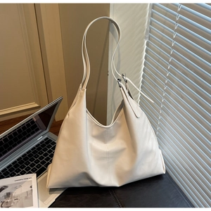 Close-up of beige faux leather tote with adjustable wide strap and silver metal buckle