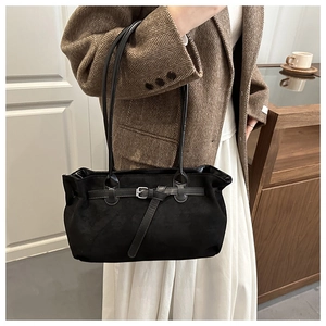 Detail of black suede tote bag with silver buckle worn with a vintage brown blazer