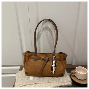 Detail view of brown matte tote bag with beaded charm and vintage buckle on knit fabric