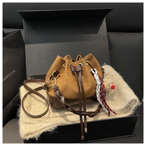 Dettaglio della borsa a secchiello retrò in pelle con tracolla intrecciata e logo dorato