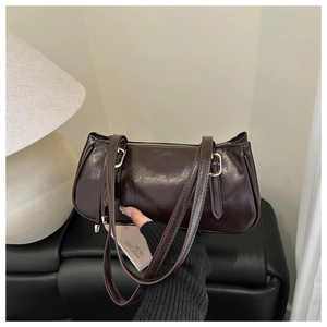 Détail d'un sac sous le bras vintage marron foncé en similicuir brillant avec boucles dorées