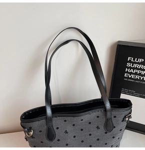 Close-up of gray canvas tote with polka dot embroidery and black leather shoulder straps