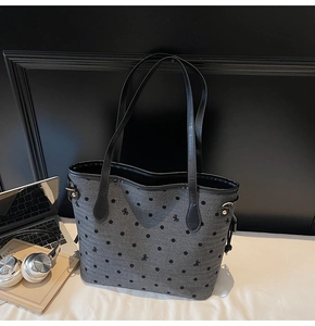 Detail of grey polka dot tote bag with bow embroidery, leather handles and silver hardware