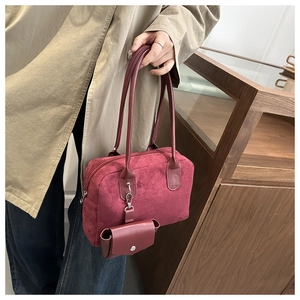 Burgundy faux suede pillow bag worn by model in a cozy indoor setting with a small pouch