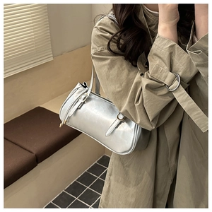 Vue latérale d'un sac baguette argenté métallisé porté par un mannequin en intérieur