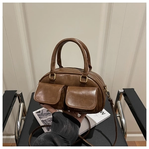 Detail view of brown vintage leather pillow bag with double front pockets and gold hardware