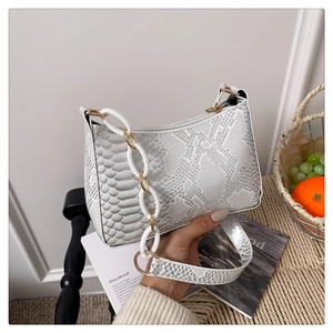 Detail of white snakeskin shoulder bag with thick acrylic chain in aesthetic setting