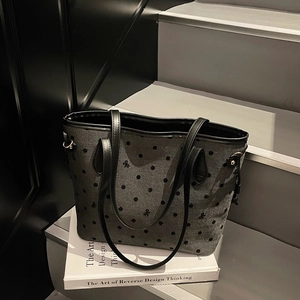 Deep grey polka dot tote bag with bow details on art books for winter commuting