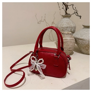 Detail of red vintage bowling bag with lace pearl bow and silver heart pendant charm