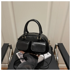 Detail of black PU leather pillow bag featuring dual front pockets and fashion text