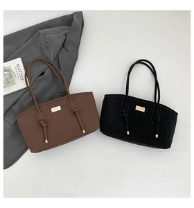 Detail view of suede tote bags with decorative knots and golden metal plates in black and brown