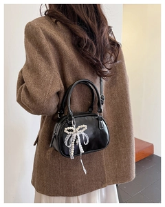 Detail of black bowling handbag with pearl bow lace pendant on a stylish brown blazer outfit