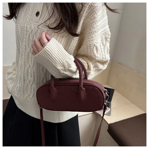 Detail of burgundy suede baguette bag with dual handles and silver hardware for women