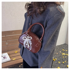 Detail of dark brown PU leather bowling bag with pearl bow charm and heart pendant