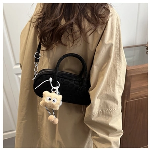 Detail of black suede hobo bag with leopard embossing and cute monster charm on model