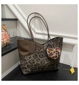 Detail of leopard print tote bag with brown faux leather trim and heart plush charm