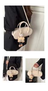 Detail of beige faux suede baguette bag featuring a playful yellow plush eye charm