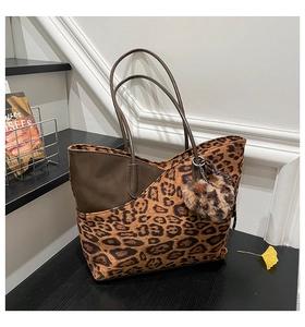 Close-up of leopard print tote bag with brown leather trim and plush ball charm decoration