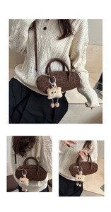 Detail of leopard print suede baguette bag with plush eye charm and slim shoulder strap