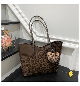 Detail of leopard print tote bag with heart charm against a vintage interior backdrop