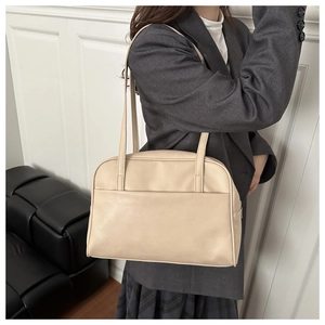 Detailed close-up of a minimalist cream PU leather tote bag worn with a gray blazer suit