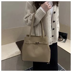 Detail of khaki leather bucket bag with metal twist lock and drawstring on white sweater