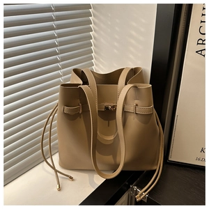 Detail of khaki leather tote bag with buckle strap under natural light and shadows