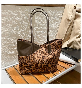 Detail of leopard print tote bag with brown faux leather trim on a wooden bench