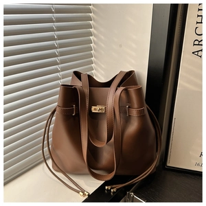 Detail view of dark brown leather bucket bag featuring gold hardware and a metal lock