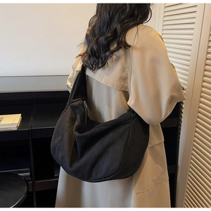 Detail of a large black crescent tote bag with a silver zipper for a minimalist style