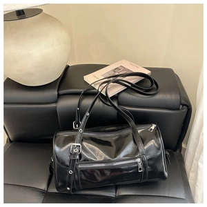 Glossy black cylinder bag detail showing shiny patent leather and silver metal zippers