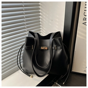 Detail of black bucket bag featuring golden twist lock and textured faux leather