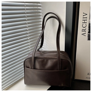Detail of a brown PU leather tote bag with front pocket and zip closure for commuting