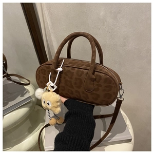 Detail of vintage leopard print suede cylinder bag with a cute plush monster charm