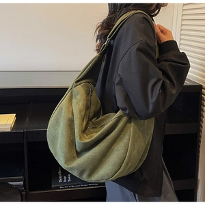 Detail view of large dark green crescent shoulder bag in soft suede fabric on model