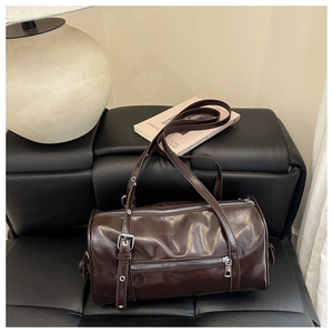 Detailed macro view of dark brown PU leather barrel bag with silver zippers and rivets