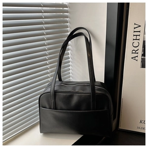 Detailed view of black leather tote bag with functional front pocket and zipper closure