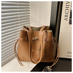 Detail of camel leather tote bag with gold twist lock and drawstring on white windowsill