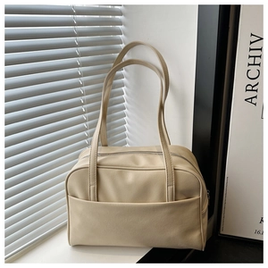 Detail of a minimalist cream PU leather tote bag with a front pocket and long shoulder straps
