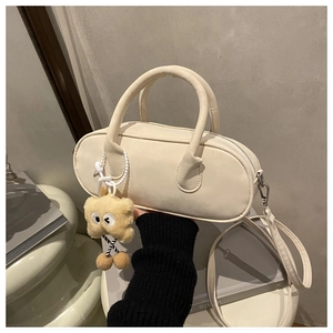Close-up of cream faux leather handbag with a cute plush cookie charm and zipper detail