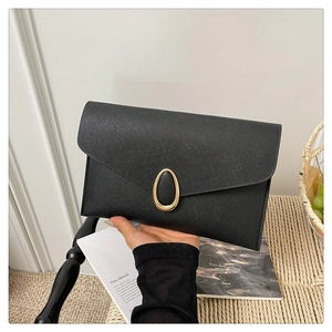 Detail of black envelope clutch with Saffiano texture and golden oval metal lock buckle