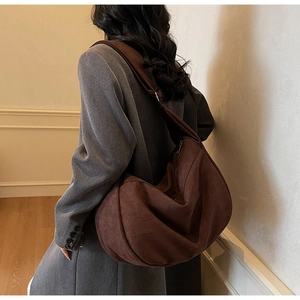 Detail of soft brown suede hobo bag with wide shoulder strap worn with a blazer